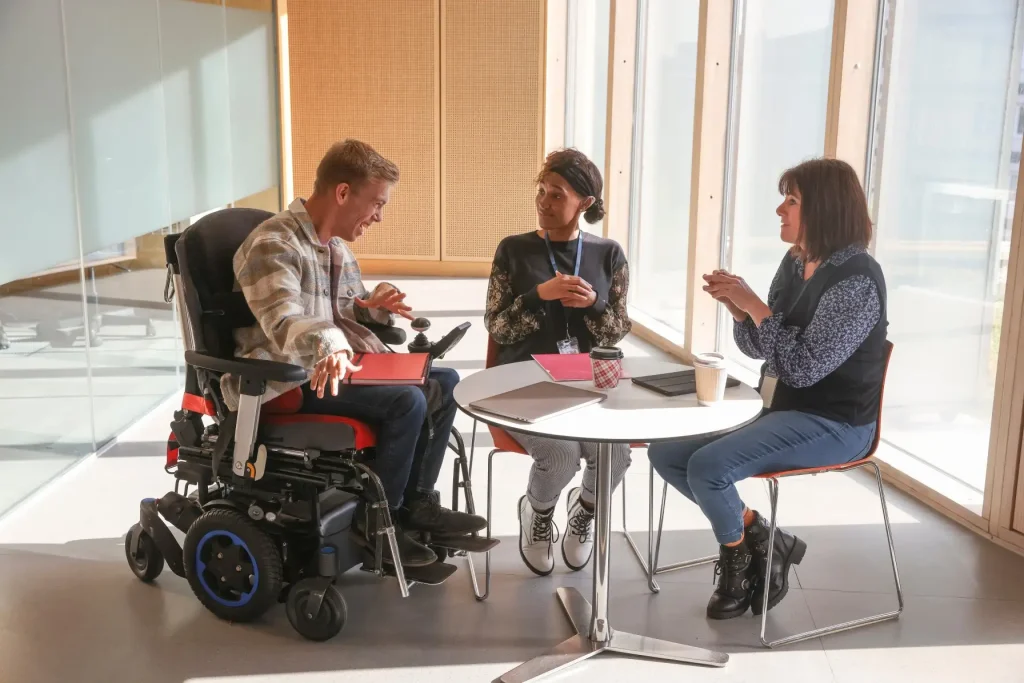 Two women talking with happy disabled man in wheelchair